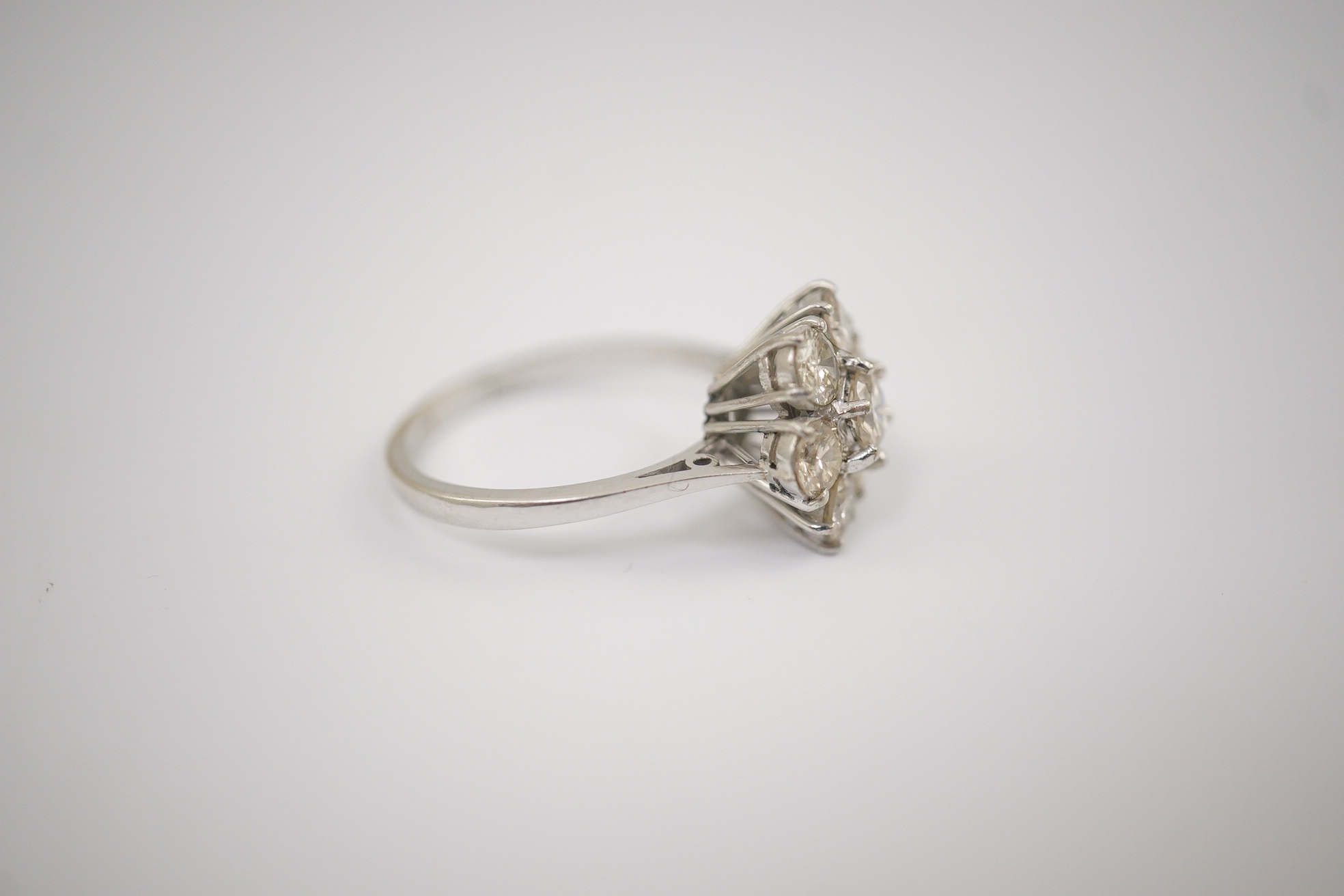 An 18ct white gold and seven stone diamond set flower head cluster ring